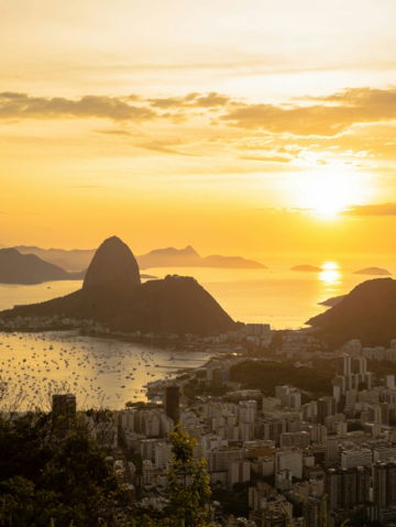 a city with a body of water and mountains in the background